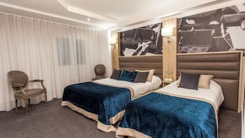 Habitación de hotel con dos camas, una silla, un escritorio y un mural grande en la pared.