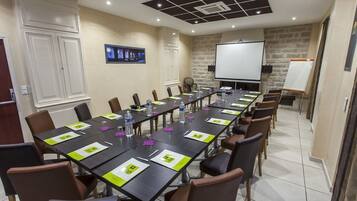 A conference room with a long table, chairs, a projector screen, and a whiteboard.