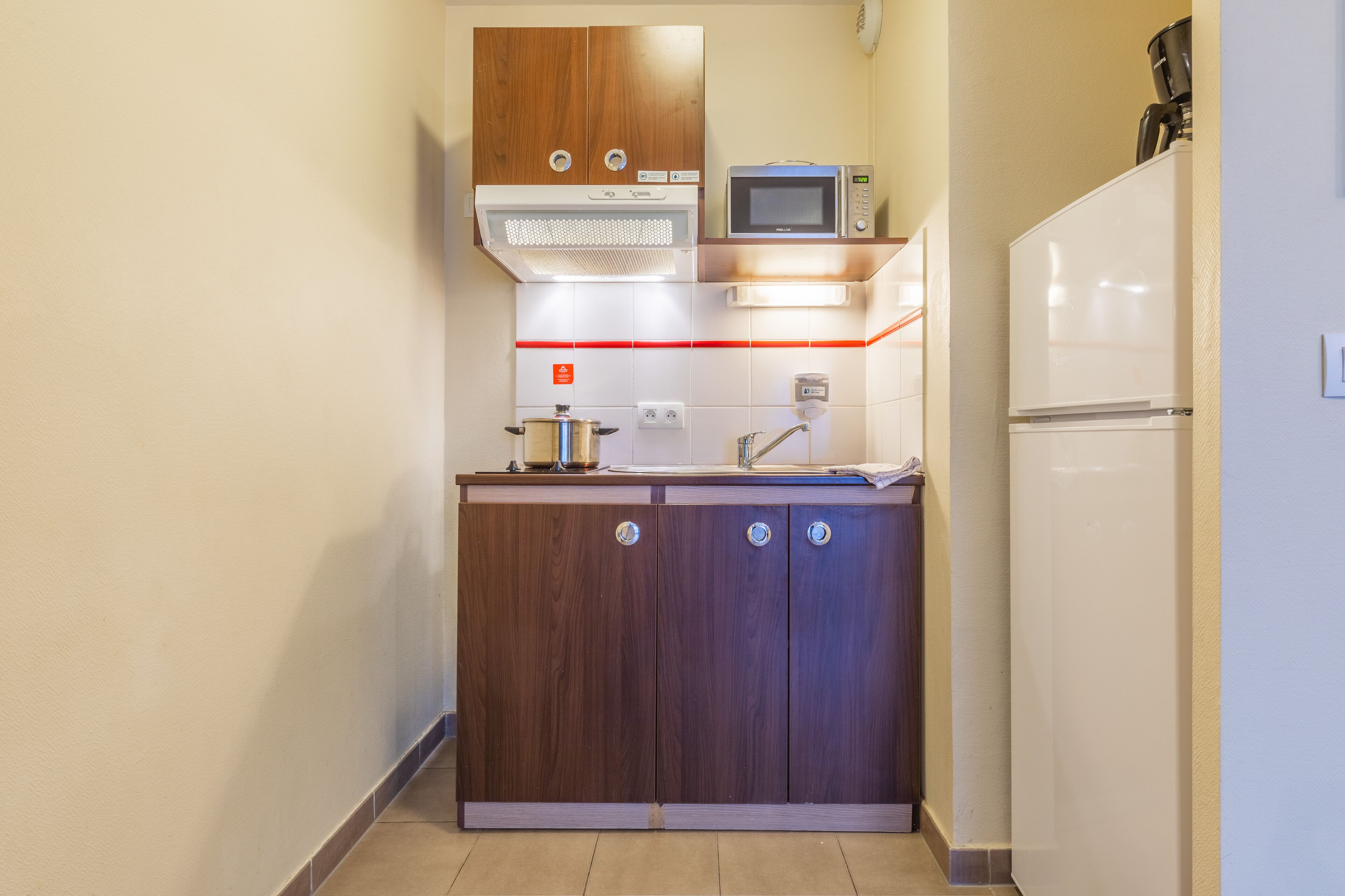 Una cocina compacta con armarios de madera, un microondas y un refrigerador.