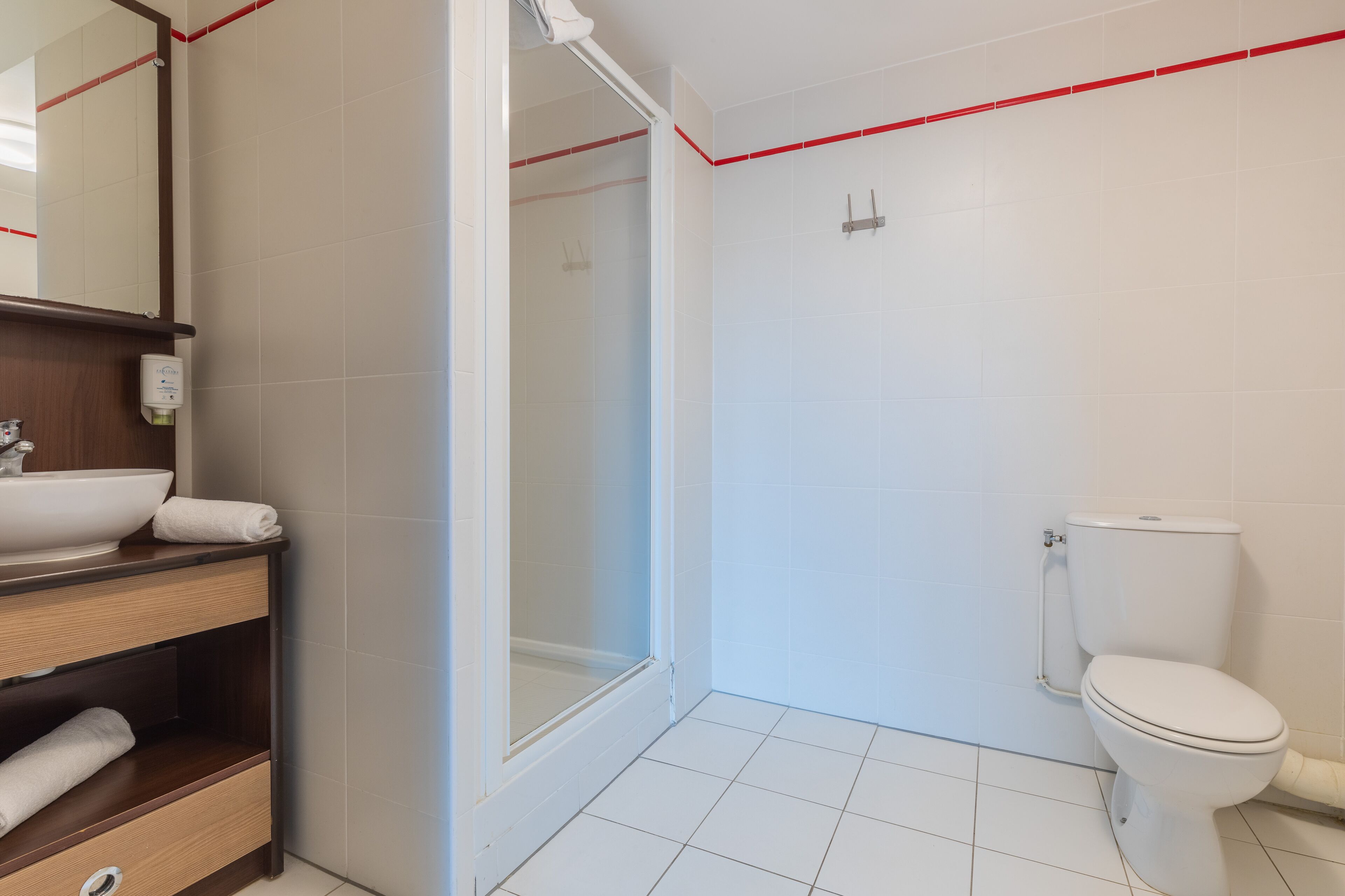 Ein modernes Badezimmer mit Waschbecken, Toilette und Dusche, alles in Weiß.