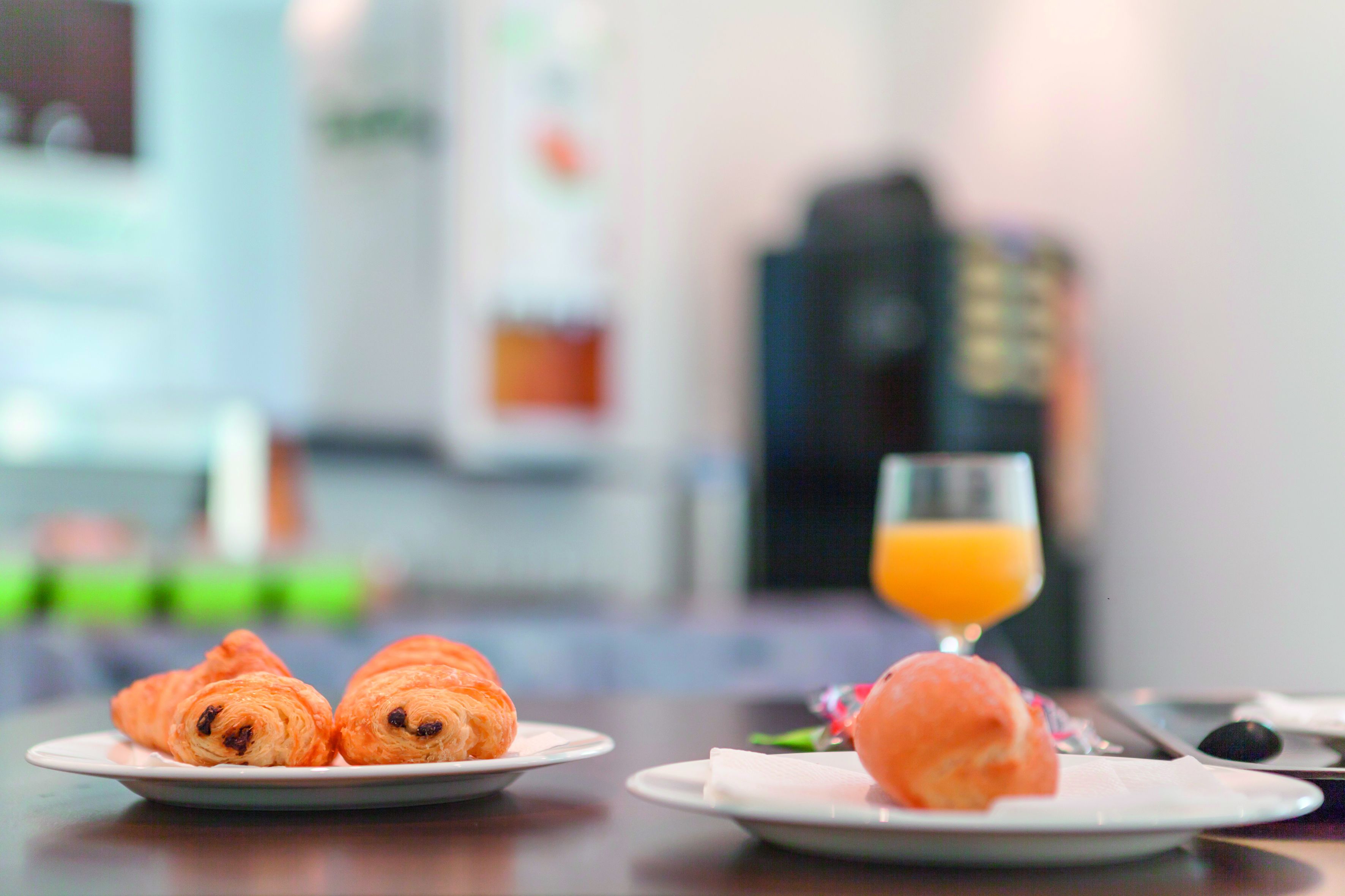 A breakfast setting with croissants and a glass of orange juice on a table.