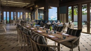Un comedor espacioso con techos altos, amplias ventanas y vista al océano.