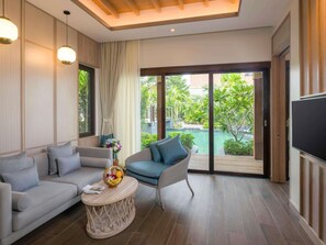Una sala moderna con un sofá, un sillón, una mesita redonda con un frutero y un televisor.