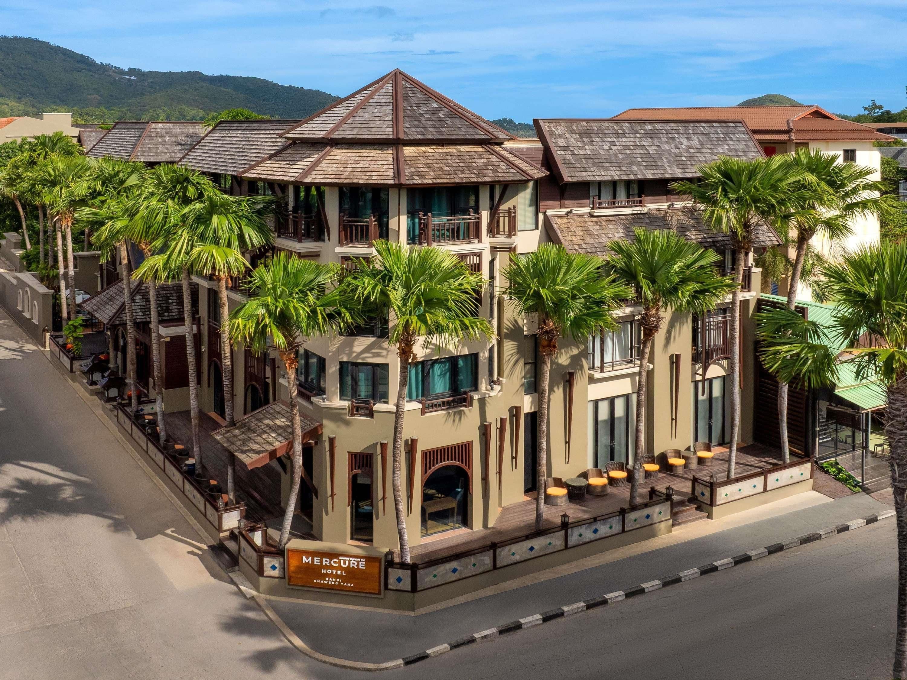 A hotel with a prominent tower, multiple balconies, and palm trees.