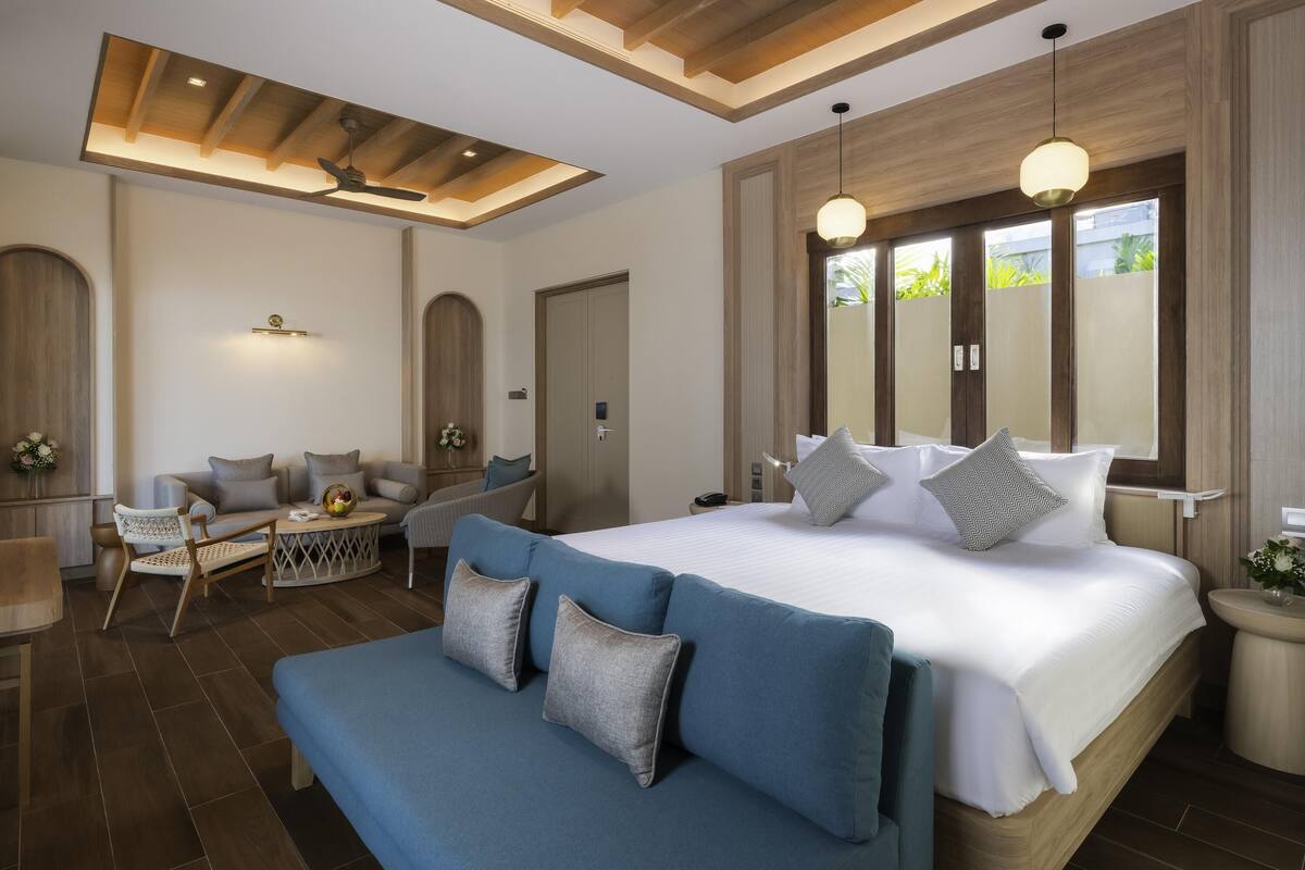 A modern bedroom with a large bed, a sofa, and a dining area.