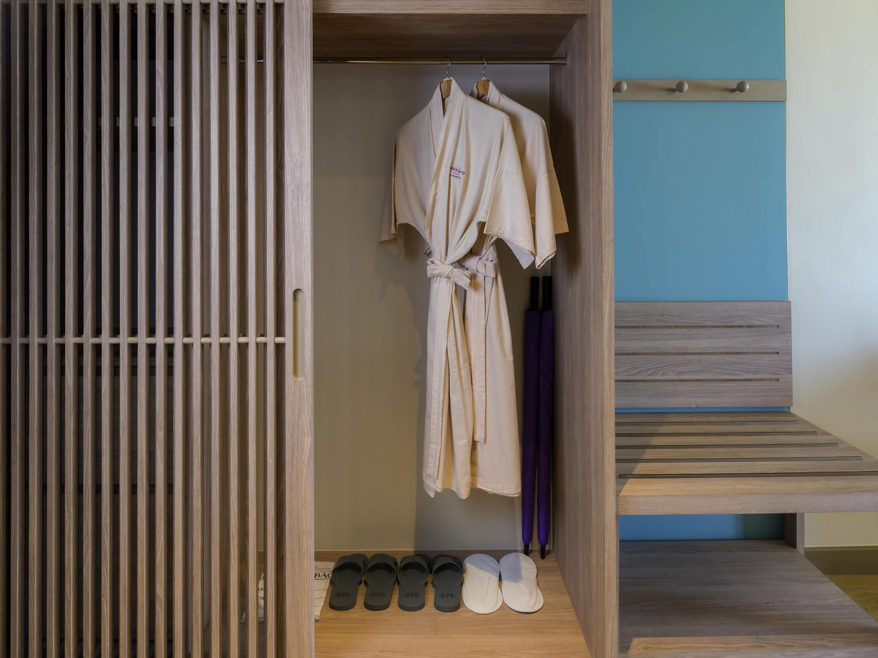A wooden wardrobe with a hanging robe and shoes.