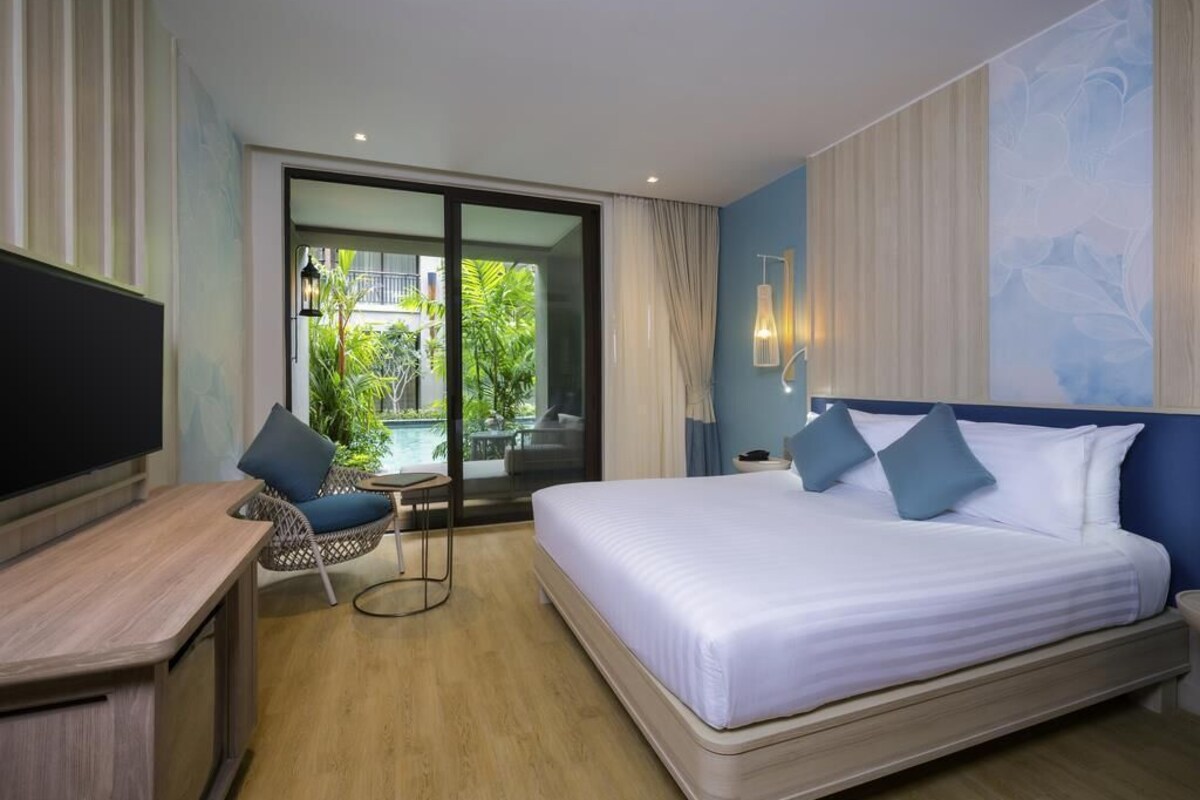 A hotel room with a bed, a TV, a small table, and a chair.