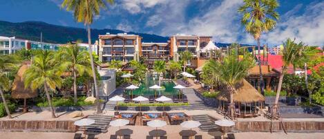 A resort with a pool, sun loungers, and palm trees.