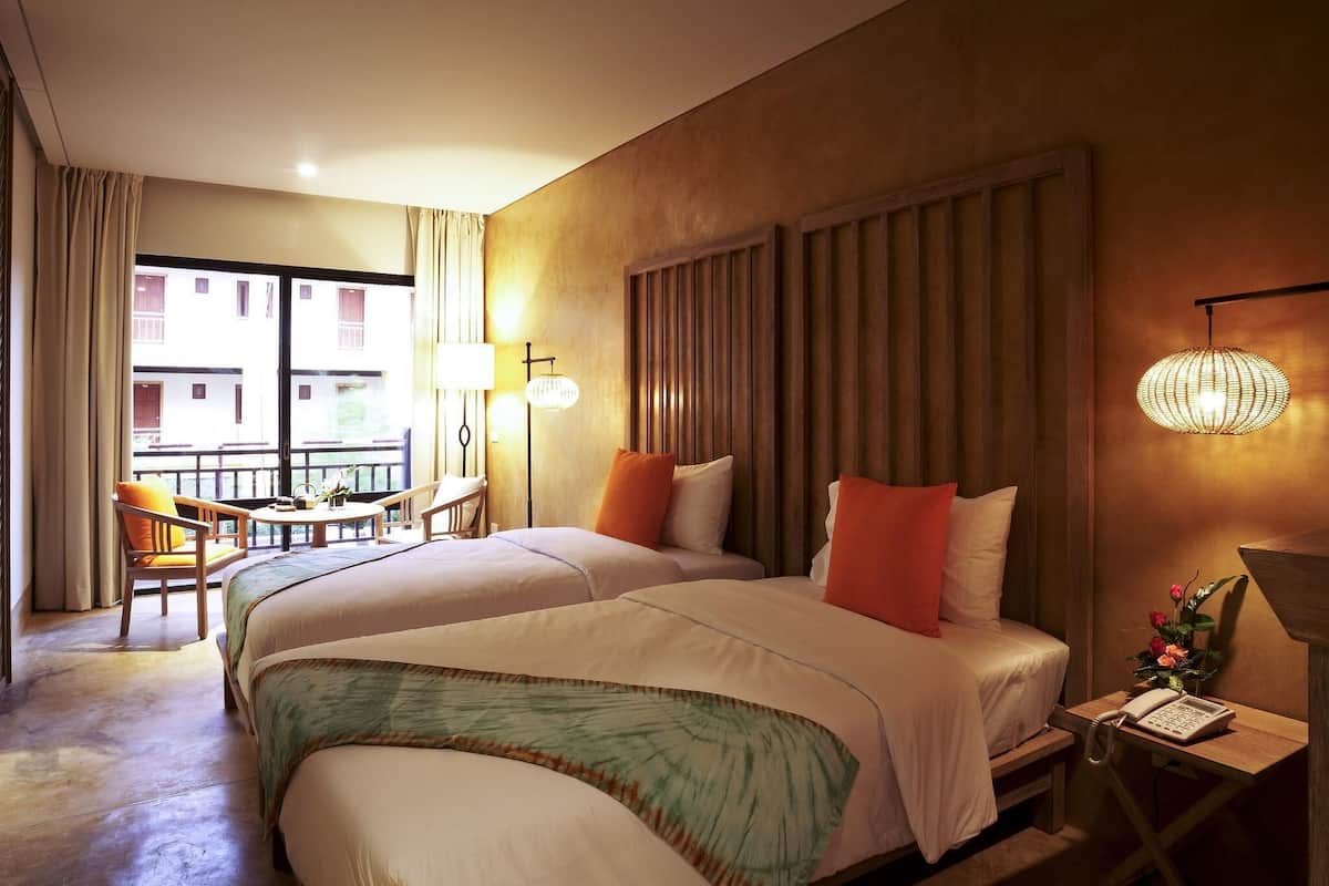 A hotel room with a large bed, a desk with a telephone, and a balcony with seating.