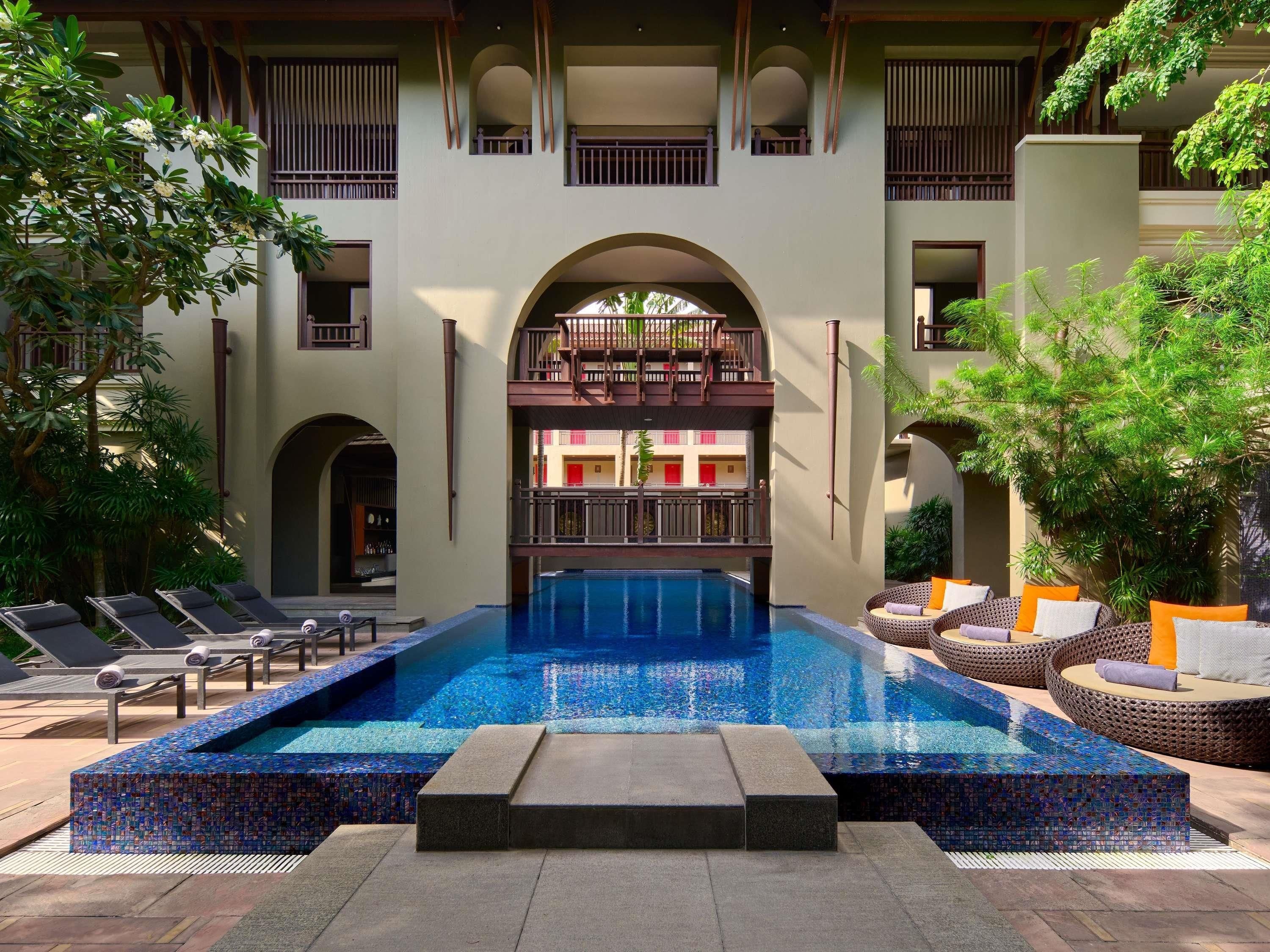 A pool area with lounge chairs and a mosaic-tiled pool.