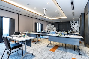 A modern conference room with multiple tables, laptops, and water bottles. - Mercure Samui Chaweng Tana Hotel (Koh Samui)