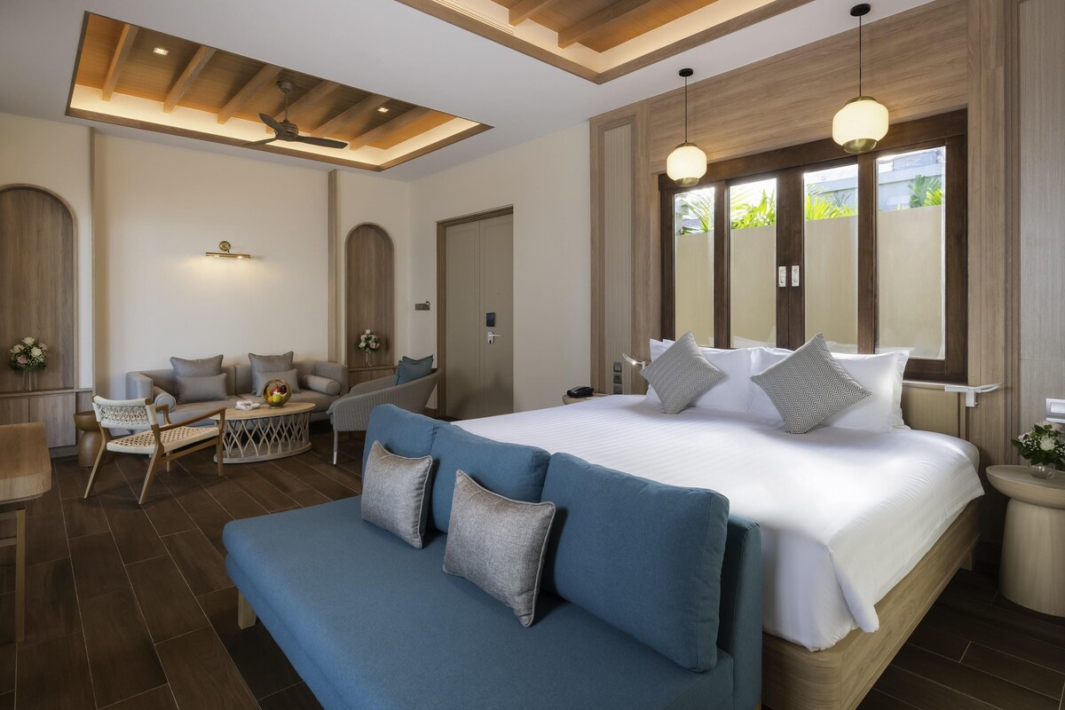 A modern bedroom with a large bed, a sofa, and a dining area.