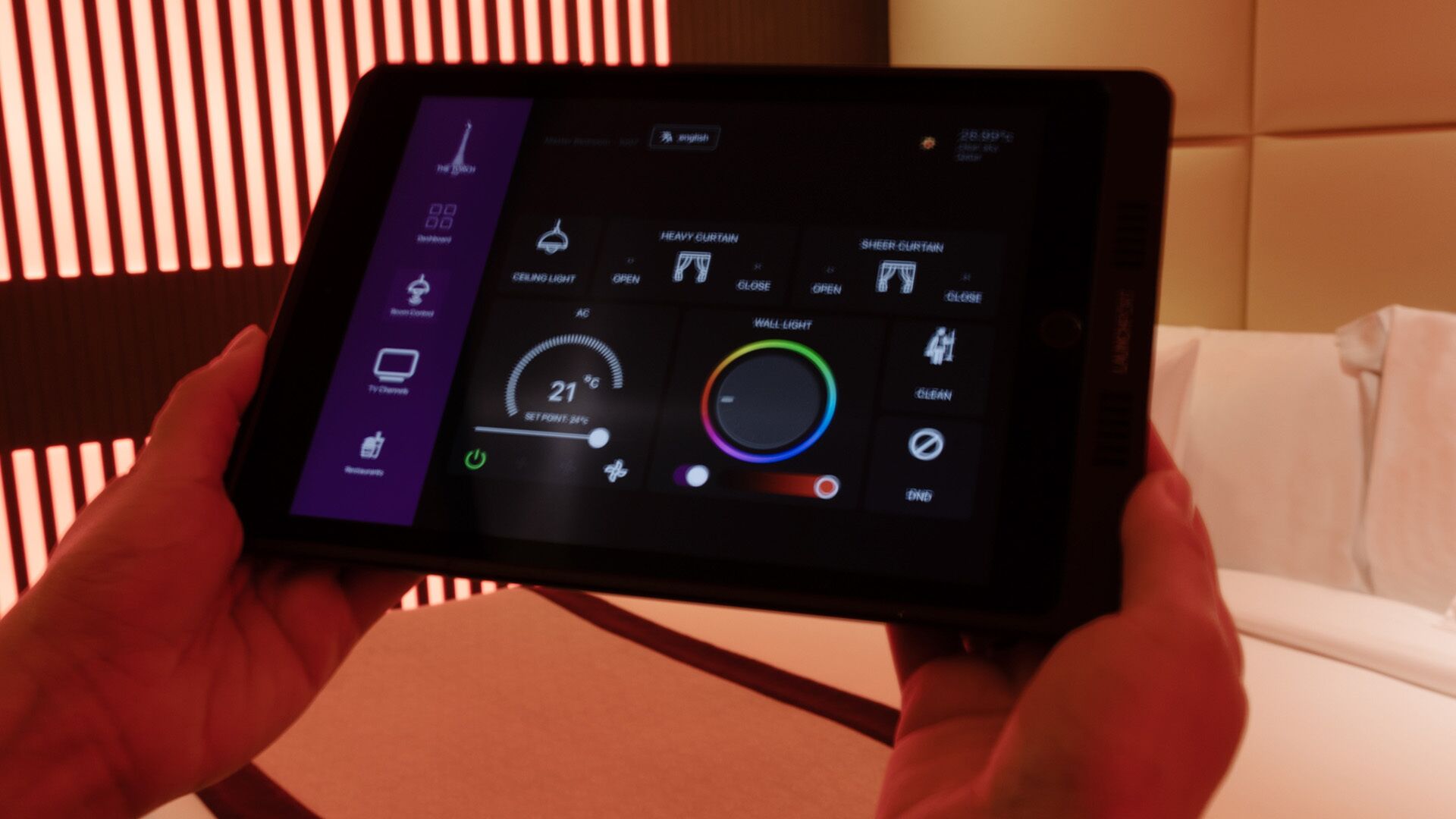 Una tableta muestra la interfaz de control de iluminación de la habitación, con opciones para la luz del techo, la luz de pared y la configuración de las cortinas.