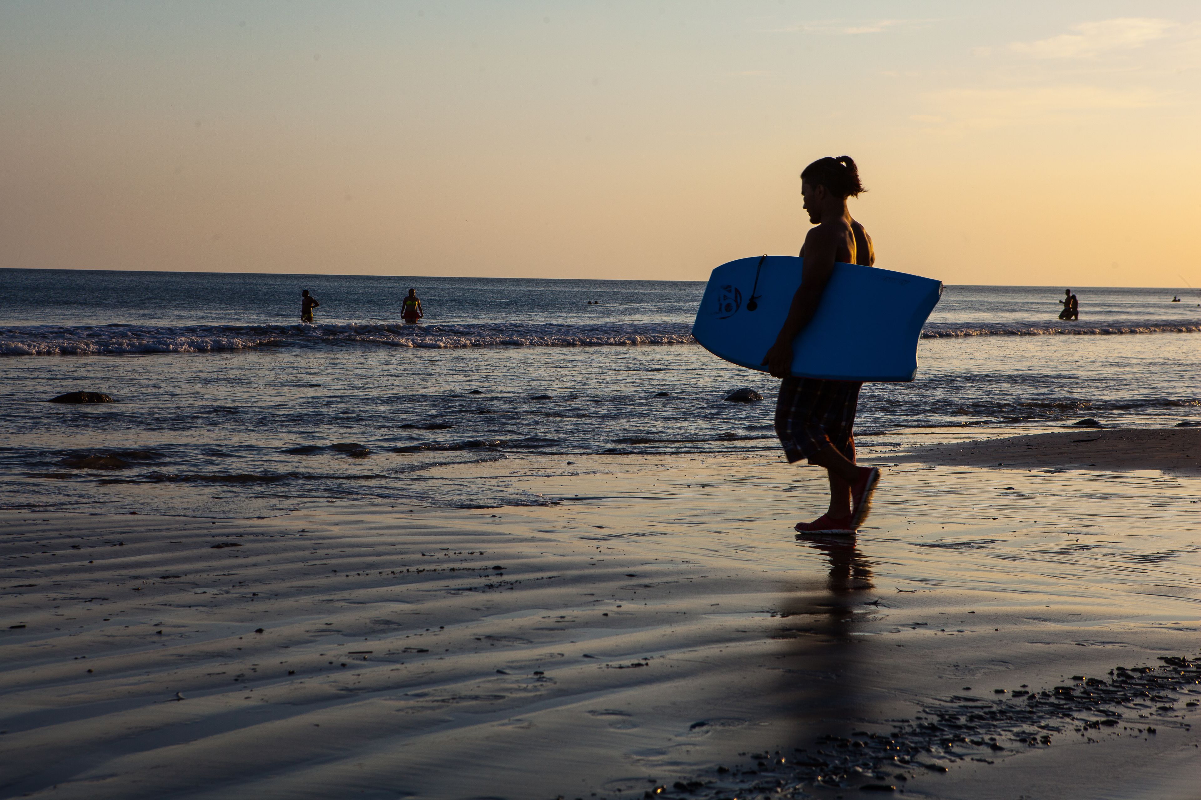 Una persona caminando sobre la playa con una tabla de surf.