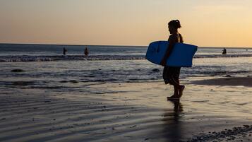 Una persona caminando sobre la playa con una tabla de surf.