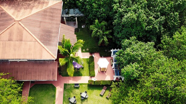 An aerial view of a property with a large building, a patio area with tables and chairs, and surrounding greenery. - Manglar Lodge (San Carlos)