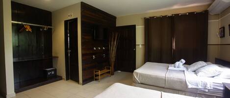 A hotel room with two beds, a wardrobe, a television, and a shower area.