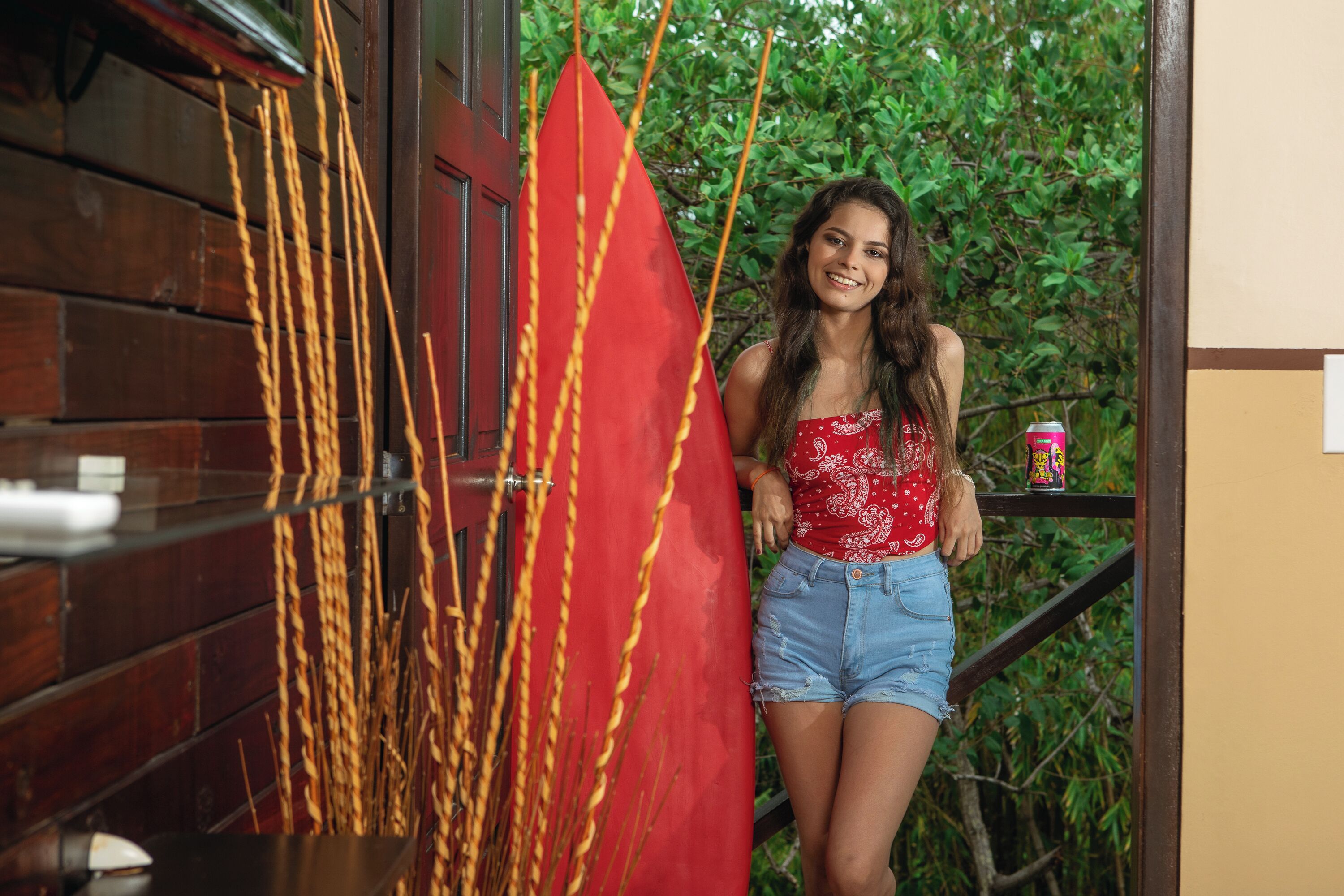 A person standing next to a red flag and a wooden wall.