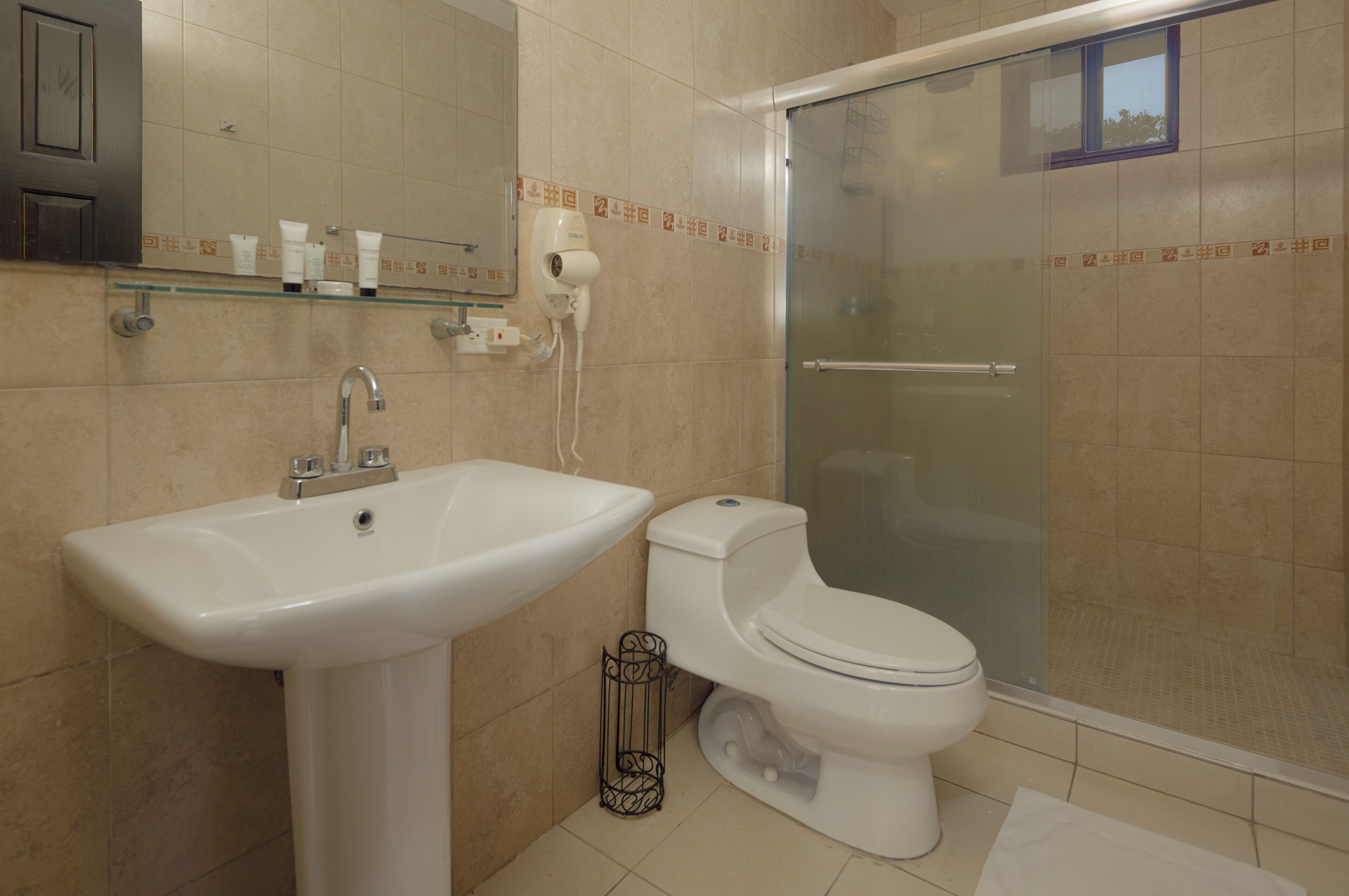 Un baño con lavamanos, inodoro y cabina de ducha de vidrio.