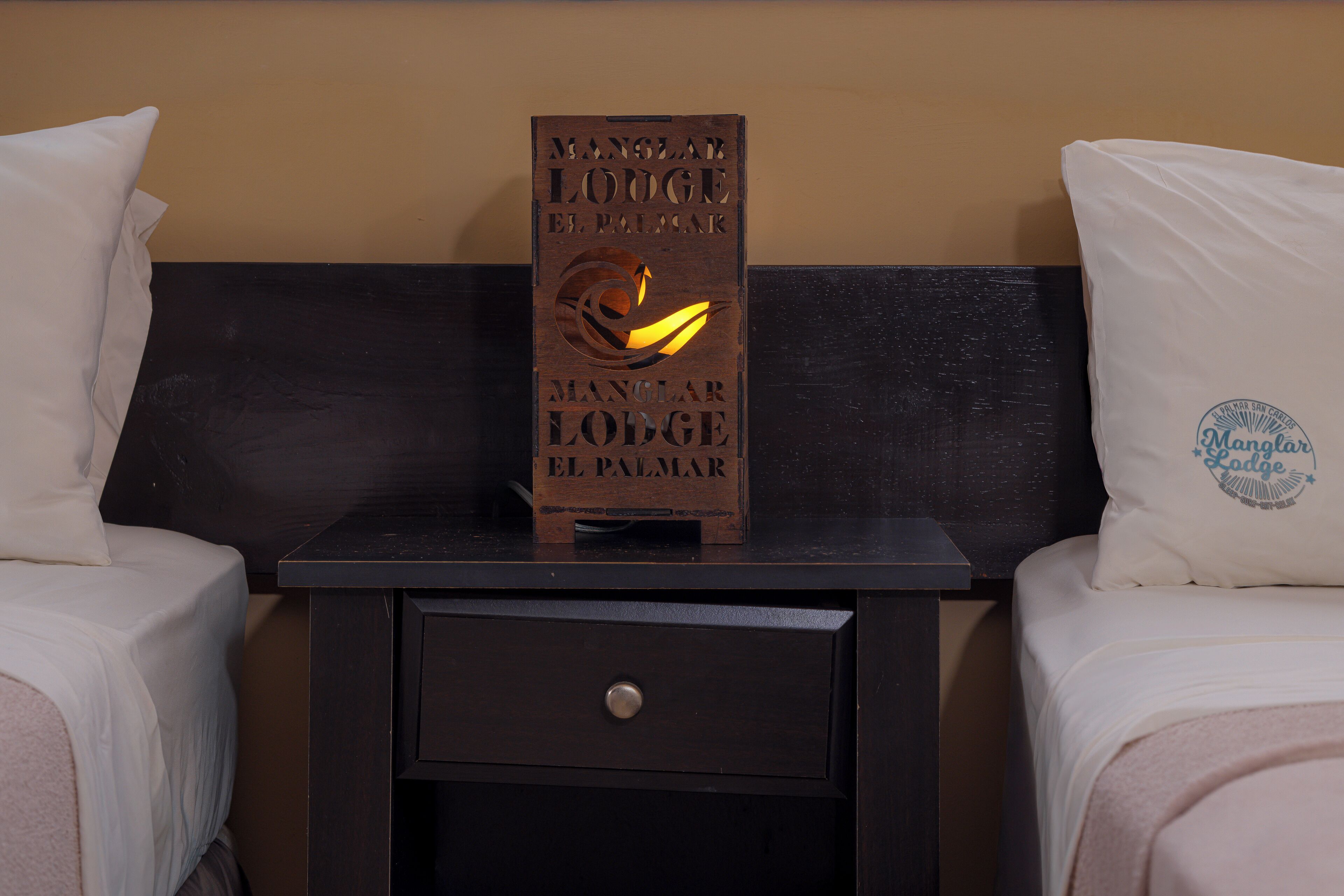 Ein Holzschild mit Text auf einem Nachttisch in einem Hotelzimmer.