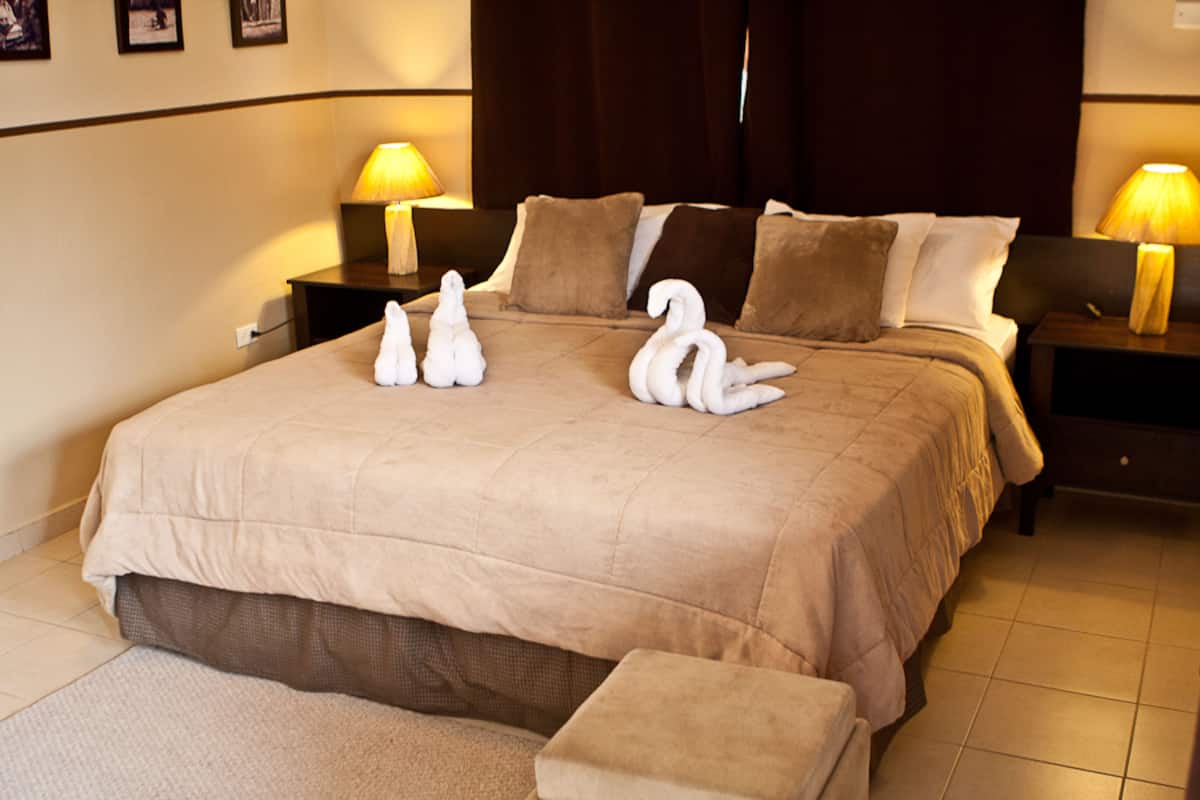 A hotel room with a large bed, two bedside tables, and a nightstand.