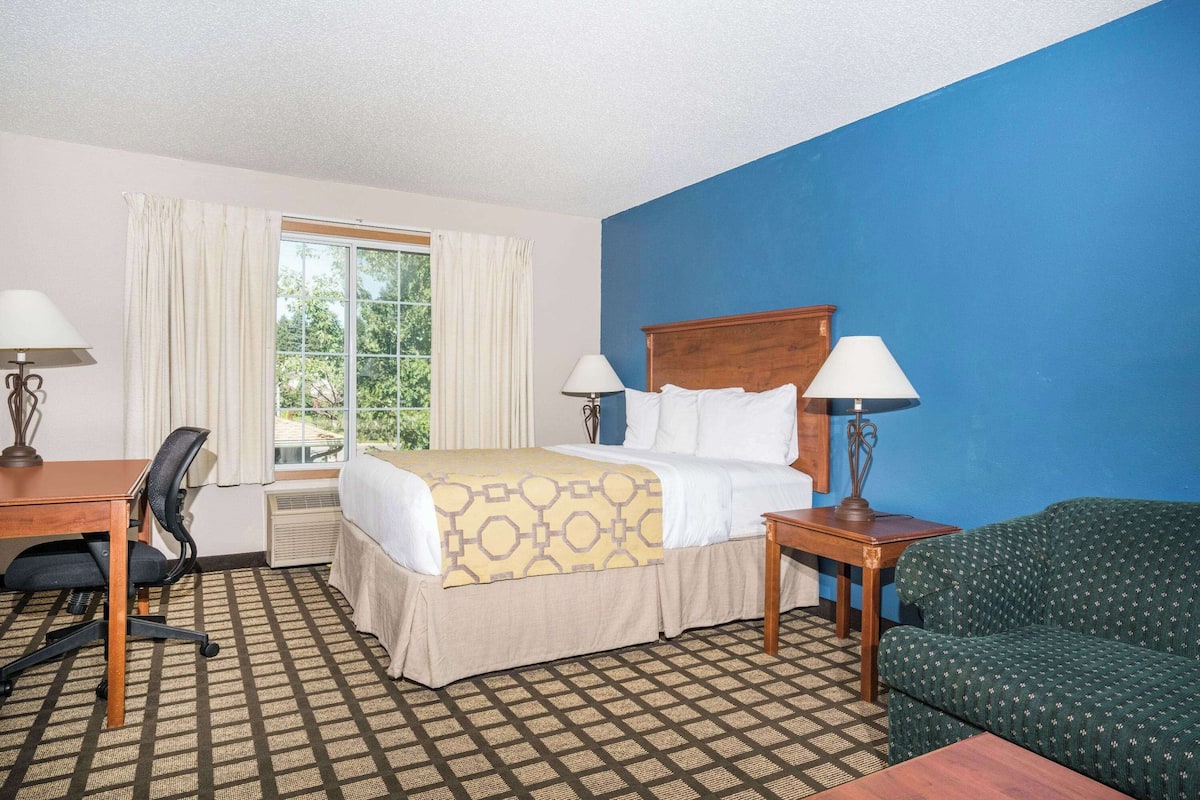 A hotel room with a bed, desk, chair, and a couch.