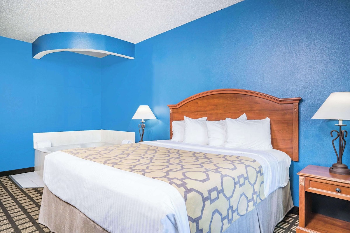 A hotel room with a large bed, a wooden headboard, two bedside tables with lamps, and a blue accent wall.