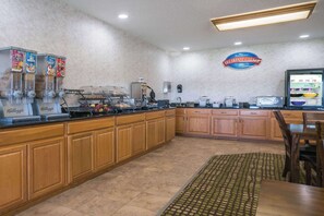 Un espacio para desayunar con mostrador, máquinas de café y un cartel que dice 'Breakfast Corner'.