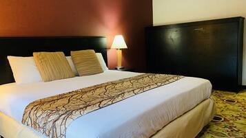 A hotel room with a large bed, a nightstand with a lamp, and a dark headboard.
