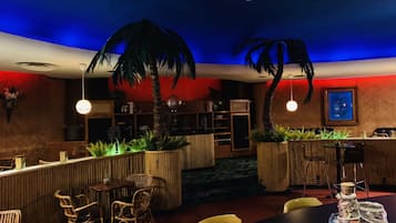 Un restaurante con zona de bar, mobiliario de madera y plantas decorativas.