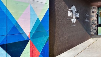Un llamativo diseño de pared geométrico y un bar Tiki con fachada de piedra.
