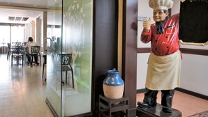 A restaurant interior with a chef statue, a vase, and a sign reading "INN CAFE". - Fersal Hotel (Quezon City)