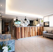 Un área de recepción con un mostrador de madera, un sofá y una planta en maceta.