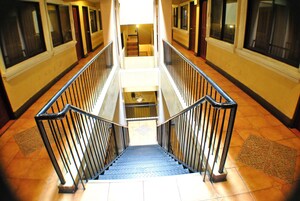 Interior de varios niveles con una escalera central flanqueada por barandillas, que conduce a una zona de descanso con piso estampado.