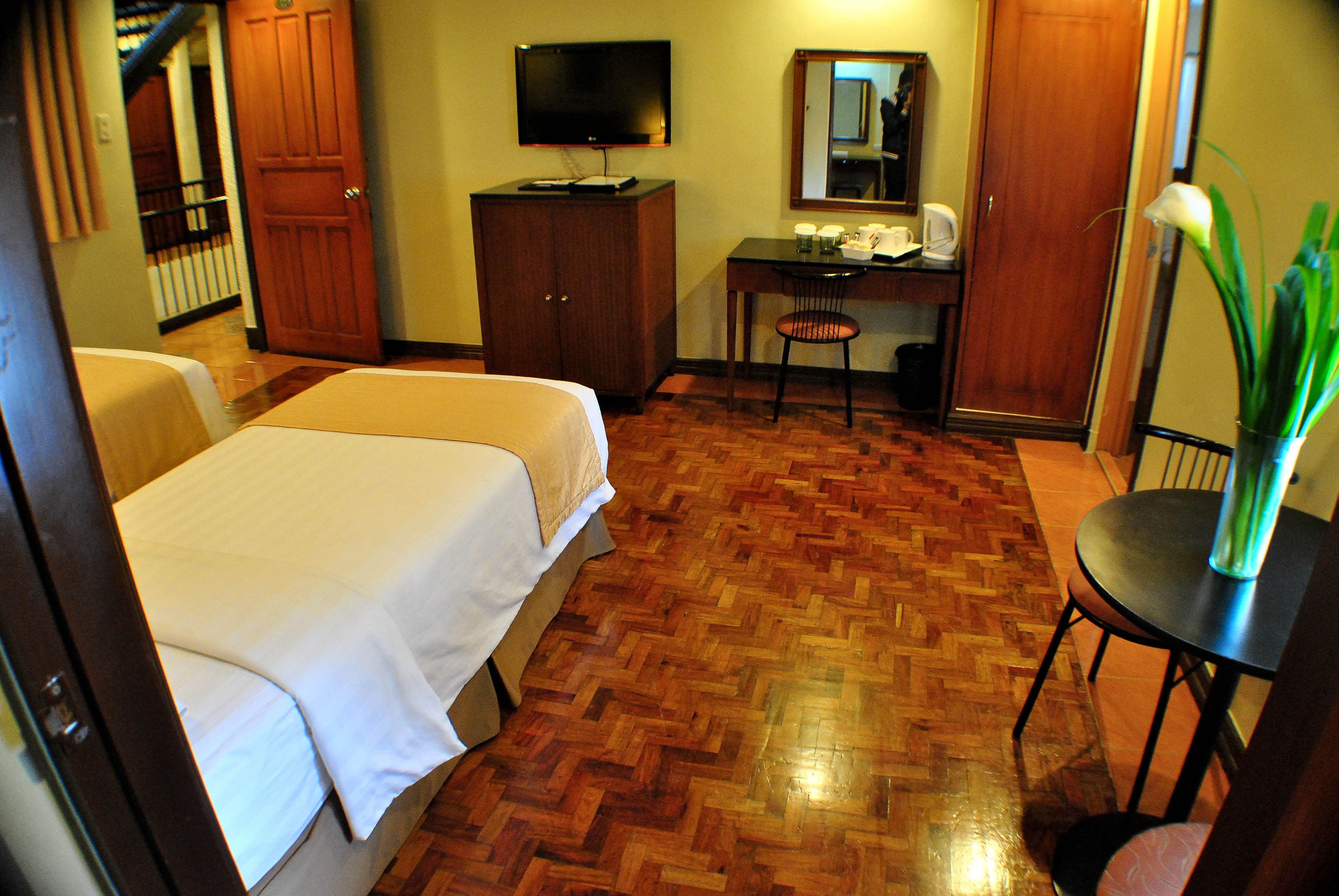 A hotel room with two beds, a desk with a chair, a television, and a mirror.