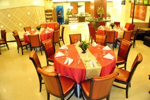 A restaurant with round tables set for dining, each with a red tablecloth and white napkins. - Hotel Elizabeth Cebu (Cebu City)