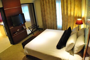 A hotel room with a bed, a television, a desk, and a lamp.