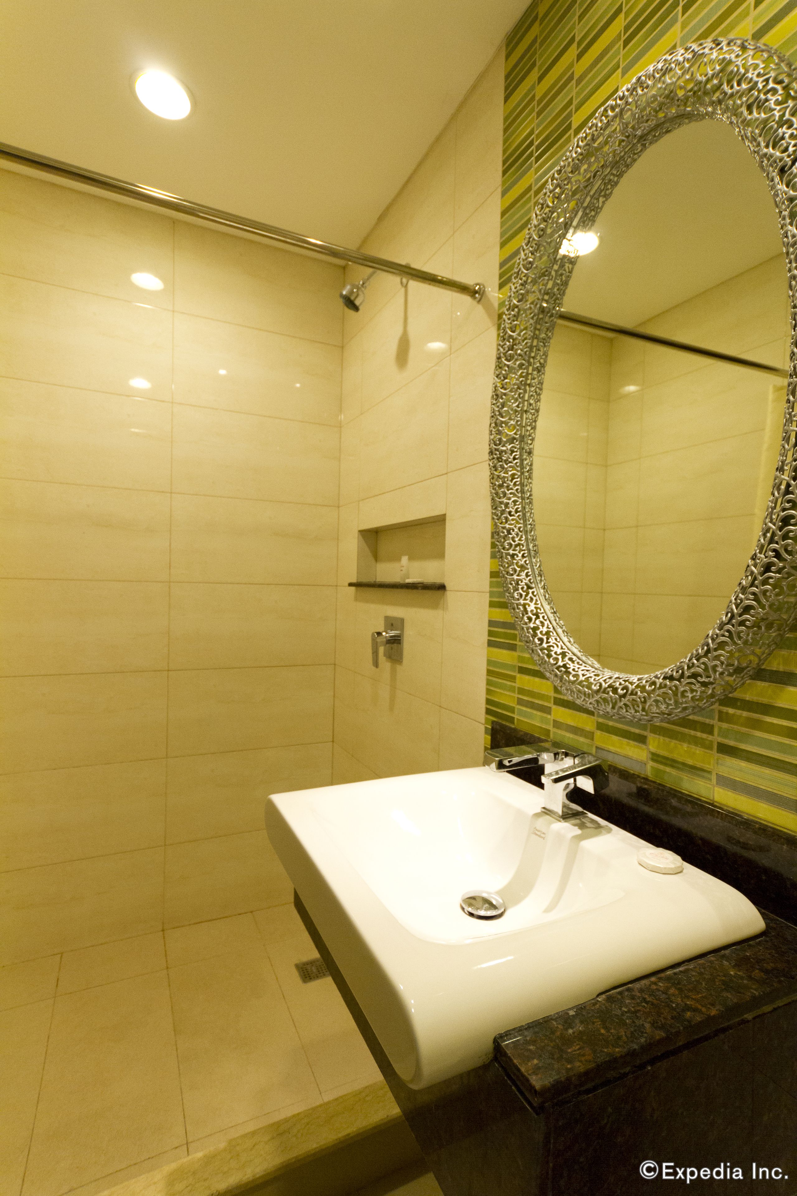 A modern bathroom with a large mirror, a white sink, and a shower area.