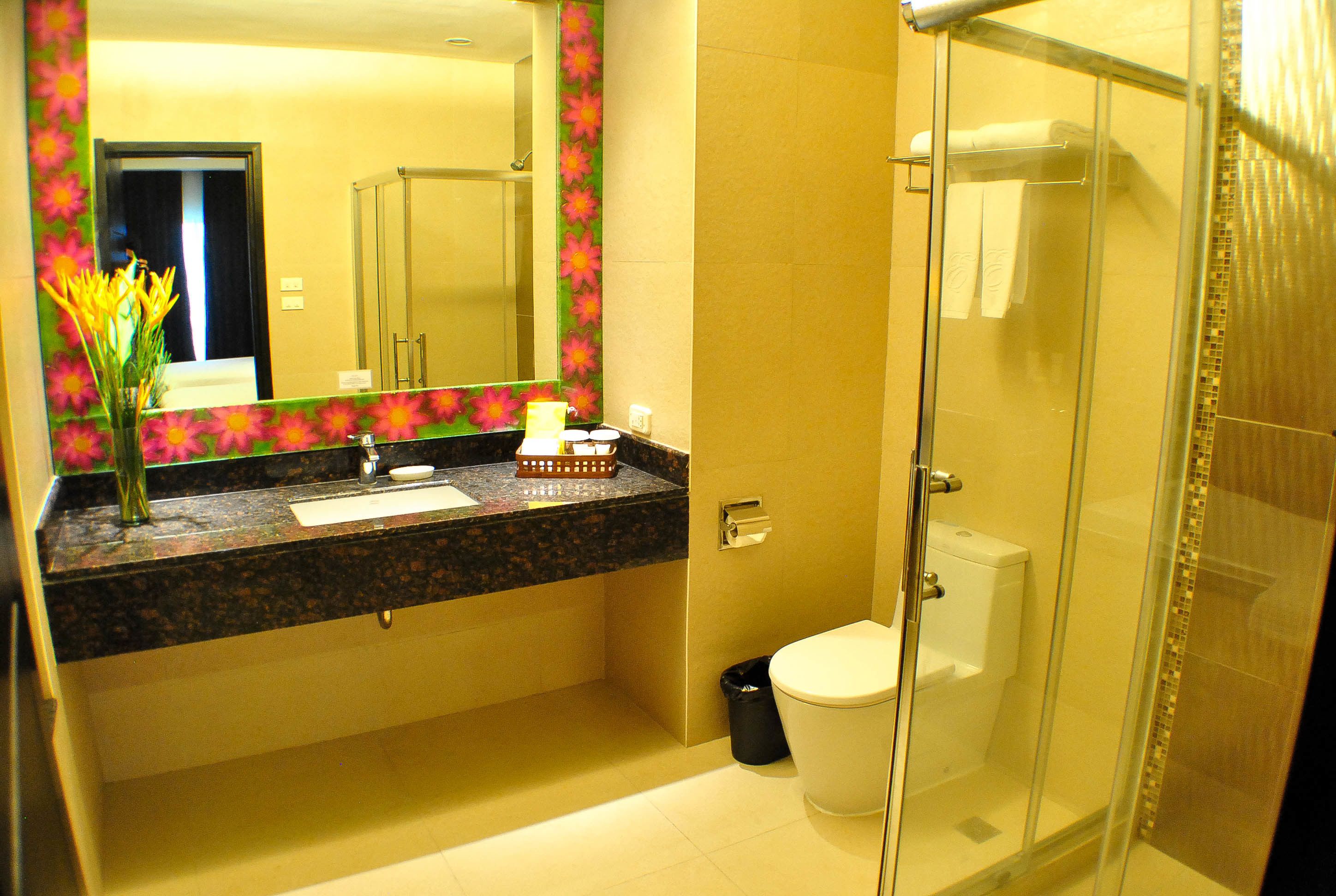 A bathroom with a marble countertop, a sink, a toilet, and a glass-enclosed shower.