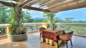 A terrace with a table set for dining, surrounded by potted plants and overlooking a scenic view. - Hotel Elizabeth Baguio (Baguio)