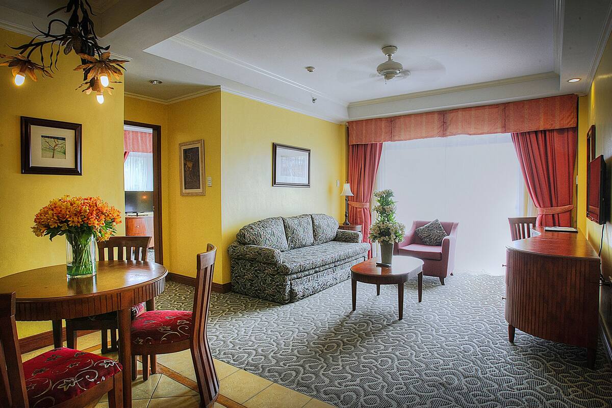 A living room with a sofa, chairs, a coffee table, and a dining table.
