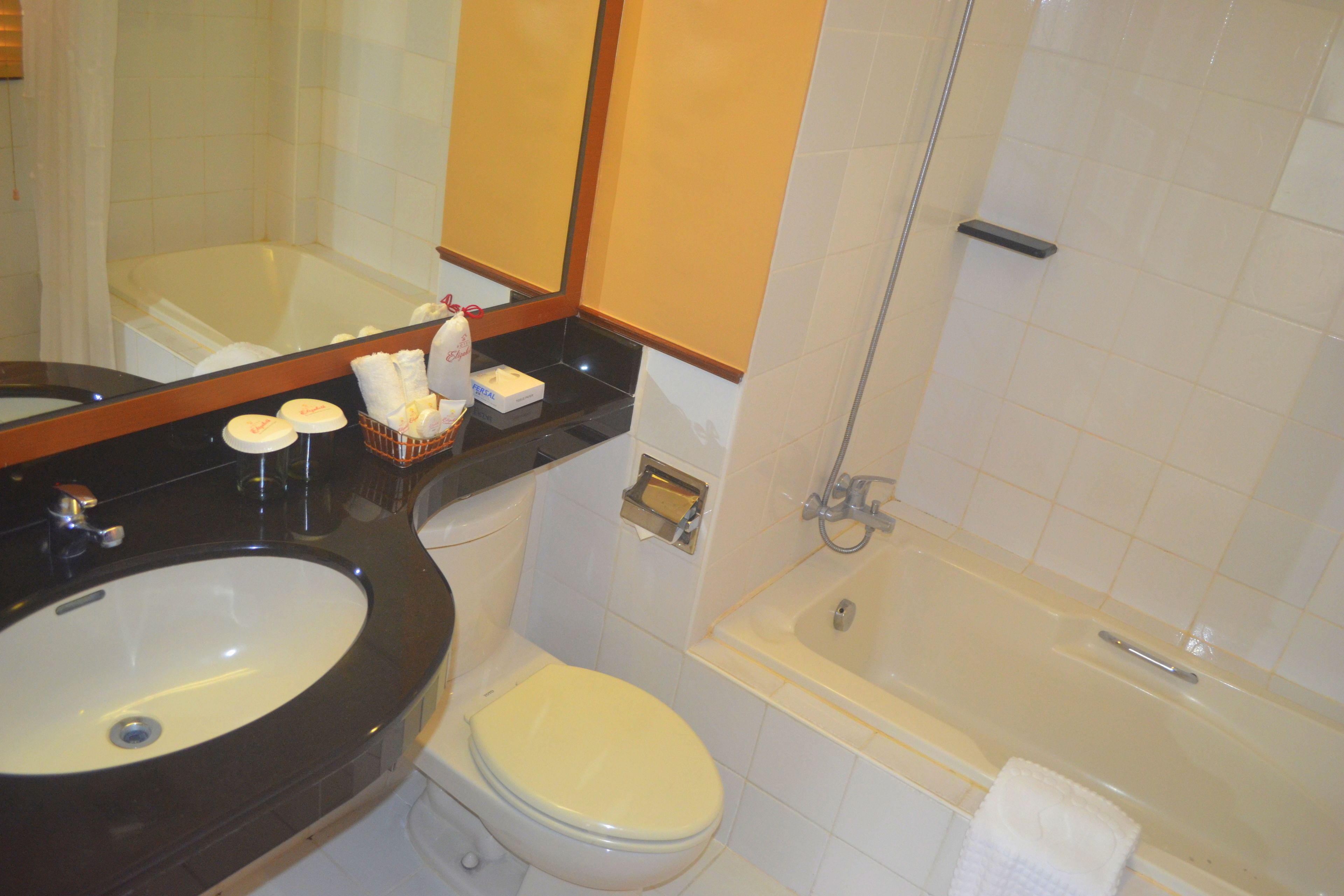 A bathroom with a sink, toilet, and bathtub. There are toiletries on the counter.