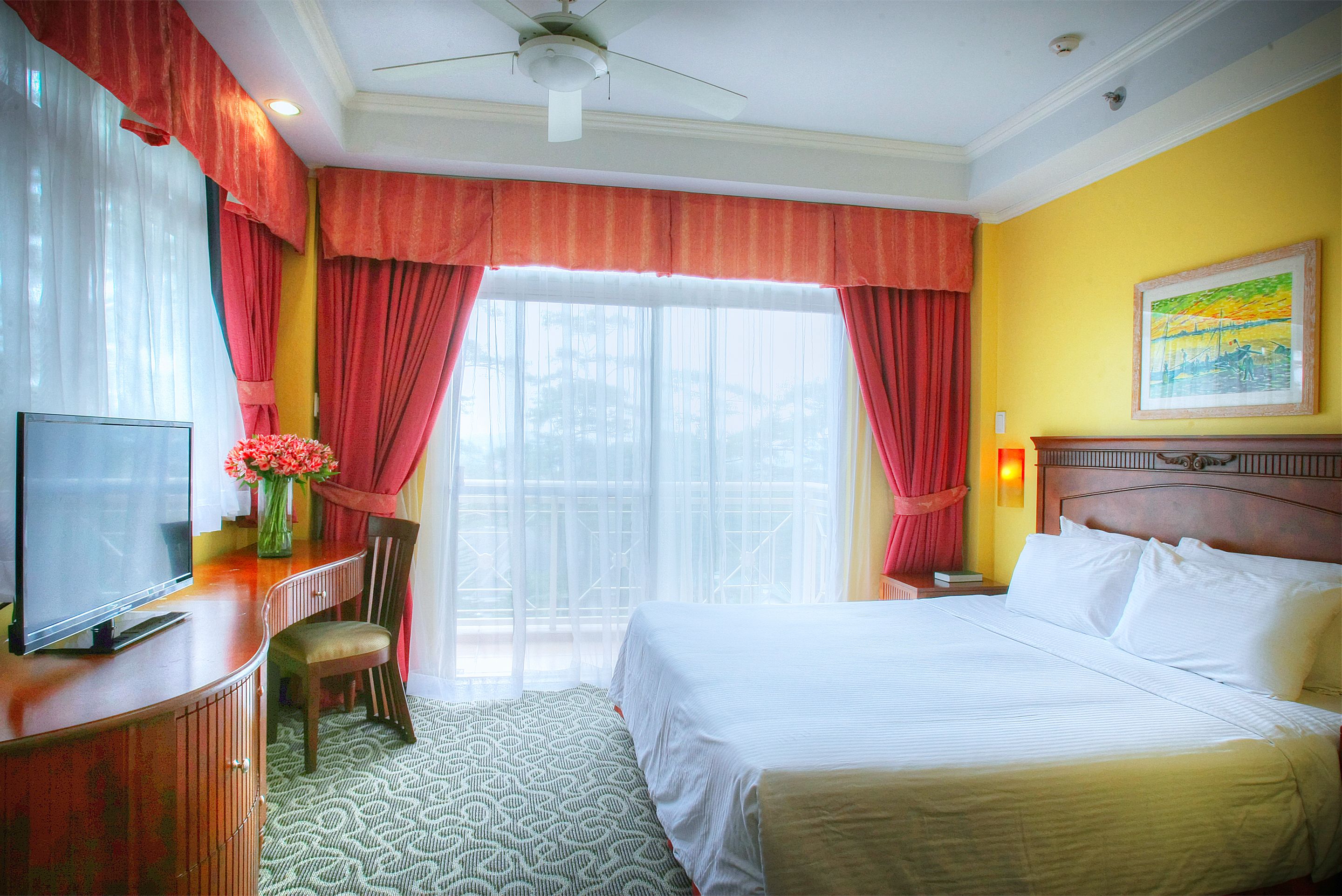 A hotel room with a bed, a TV, a desk, and a chair.