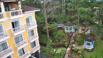 Un edificio de varios pisos con balcones, un jardín con plantas en macetas y un mirador.