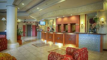 A hotel lobby with a reception desk, seating area, and decorative elements.