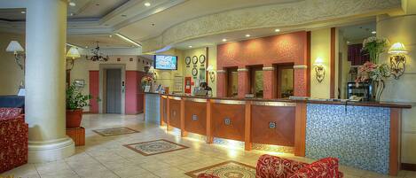 A hotel lobby with a reception desk, seating area, and decorative elements.