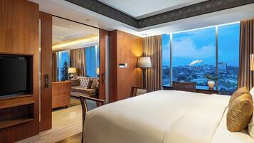 A hotel room with a large bed, a TV, a desk, and a view of the cityscape.