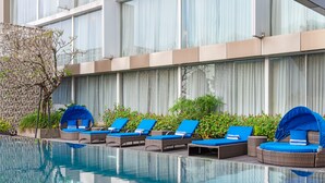 Un área de piscina con sillas de descanso y una pared decorativa.