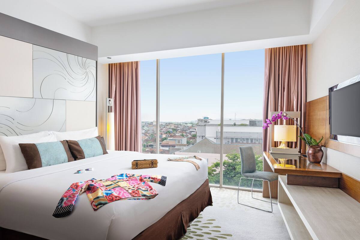 Una habitación de hotel moderna con una cama grande, un escritorio, una silla y un televisor.
