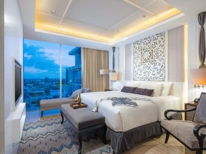 Une chambre d’hôtel moderne dotée d’un grand lit, d’un coin salon, d’une vue sur la ville et d’un panneau mural décoratif.